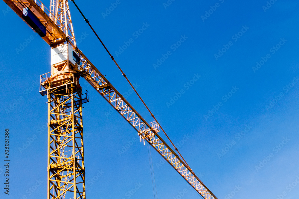 Construction crane tower on blue sky background. Crane and building working progress. Worker. Construction concept. New buildings with a crane. Tower crane