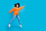 Full length photo of lovely young lady jumping flying have fun wear trendy knitwear orange garment isolated on blue color background