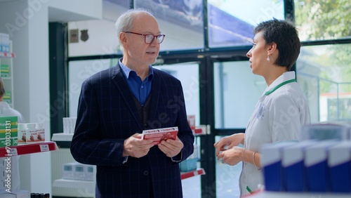 Принти на полотні Aged man in chemist store asking pharmacist for medical opinion, needing treatment for cardiovascular issues