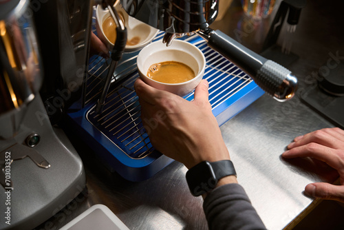 Barista pouring espresso using coffee machine for brewing hot beverage