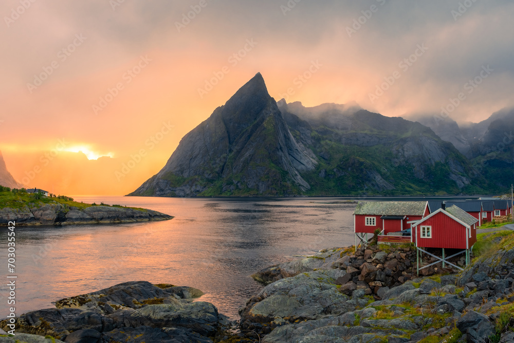 Amazing sunset through the mist and the Reinebringen Mount over the red houses of Hamnoy, Lofoten Islands, Norway
