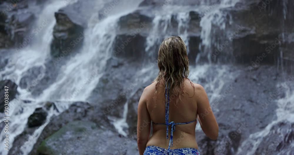 A young woman in a swimming suit at Kanto Lampo waterfall in lush tropical forest, Bali, Indonesia A young woman in a swimming suit at Kanto Lampo waterfall in lush tropical forest, Bali, Indonesia