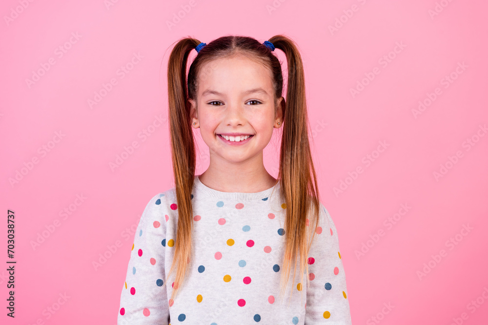 Photo of good mood nice adorable small girl with tails hairstyle wear stylish dotted sweatshirt smiling isolated on pink color background