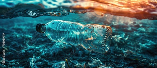 Blue water polluted by a drifting plastic bottle in sunlight; an environmental problem.