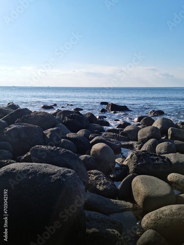 This is a Jeju beach with blue skies and basalt rocks. © binimin