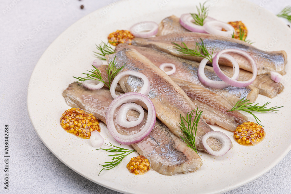Salted herring with dijon mustard, dill and red onion rings. Marinated filleted fish on light stone Salted herring with dijon mustard, dill and red onion rings. Marinated filleted fish on light stone