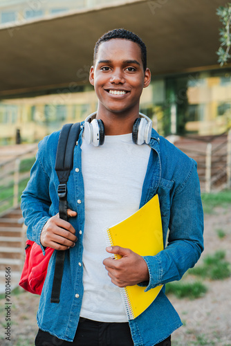 Foto Vertical individual portrait of a african american student young man carrying a backpack and note books at university campus