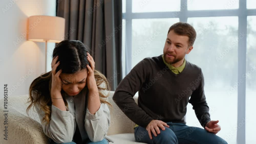 Caucasian couple sitting on sofa in living room, quarreling over disagreement, man yelling at woman, woman experiencing psychological abuse from her husband Caucasian couple sitting on sofa in living room, quarreling over disagreement, man yelling at woman, woman experiencing psychological abuse from her husband