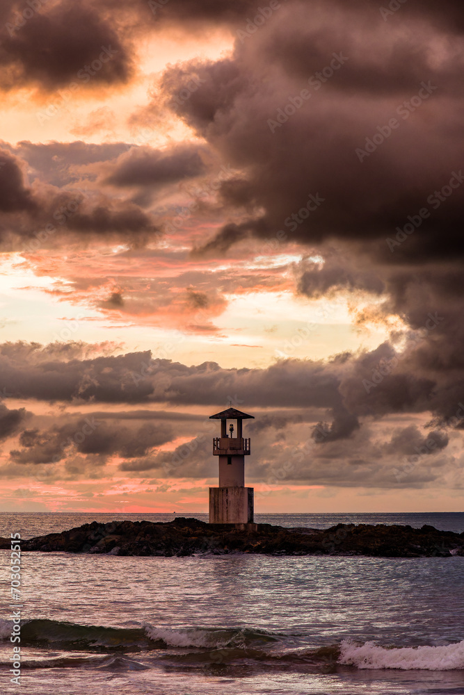 Storm clouds behind a small lighthouse during a tropical sunset