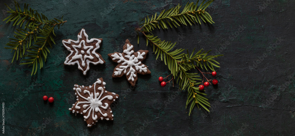 Banner, Christmas shortbread cookies decorated with icing decorated with Christmas tree branches and red berries on a dark green background, Christmas wallpaper, blank space for text, wishes. Banner, Christmas shortbread cookies decorated with icing decorated with Christmas tree branches and red berries on a dark green background, Christmas wallpaper, blank space for text, wishes.