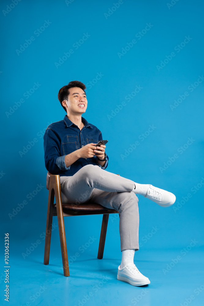 Portrait of young Asian business man posing on blue background Portrait of young Asian business man posing on blue background