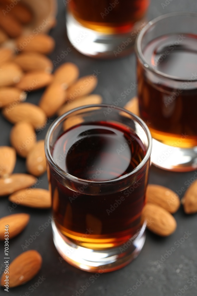 Glasses with tasty amaretto liqueur and almonds on dark gray table, closeup Glasses with tasty amaretto liqueur and almonds on dark gray table, closeup