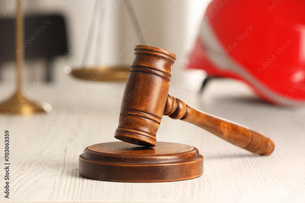 Law concept. Gavel, scales and red hard hat on white wooden table, closeup Law concept. Gavel, scales and red hard hat on white wooden table, closeup