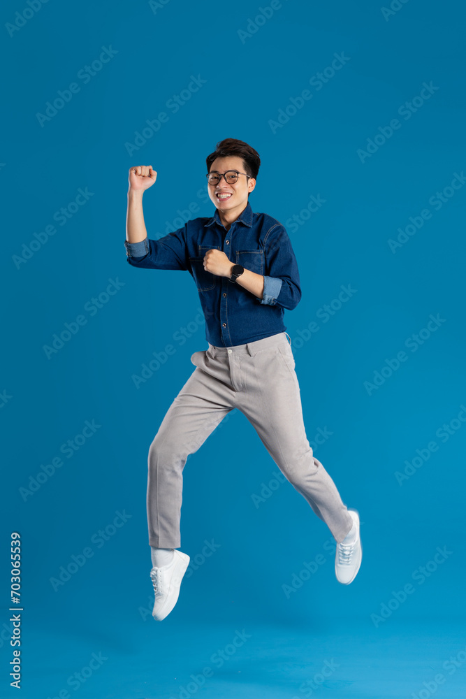 Portrait of young Asian business man posing on blue background