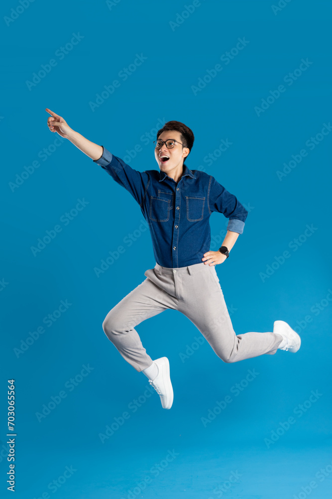 Obraz premium Portrait of young Asian business man posing on blue background