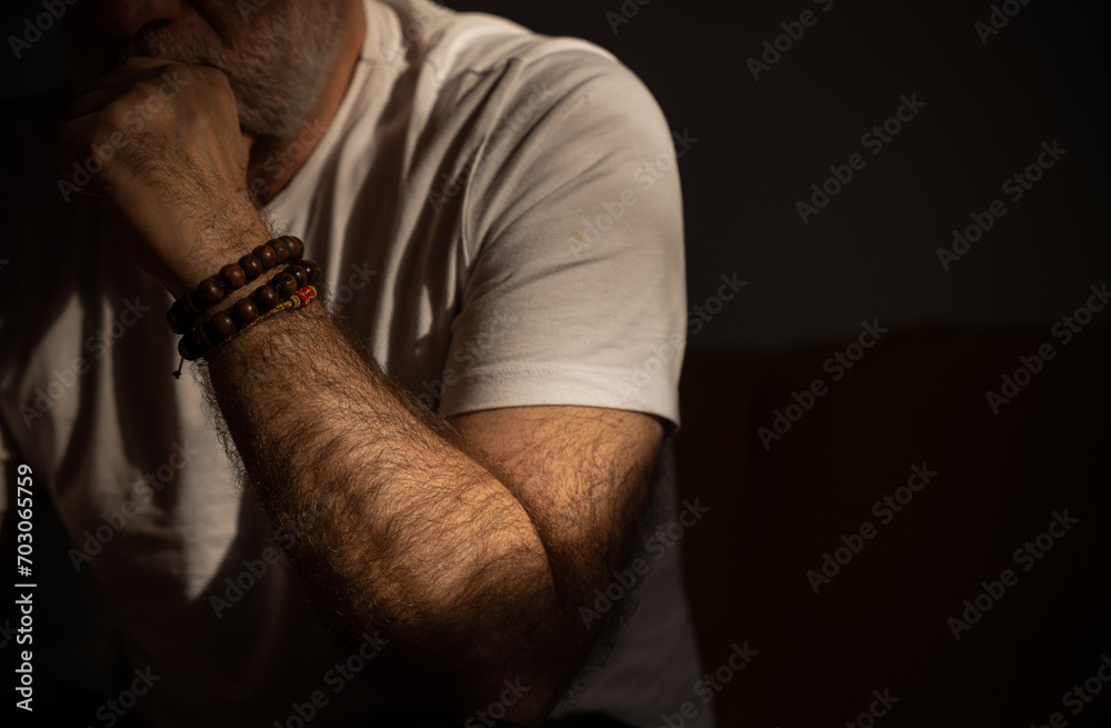 Portrait of mature man sitting on sofa with bracelets on wrist Portrait of mature man sitting on sofa with bracelets on wrist