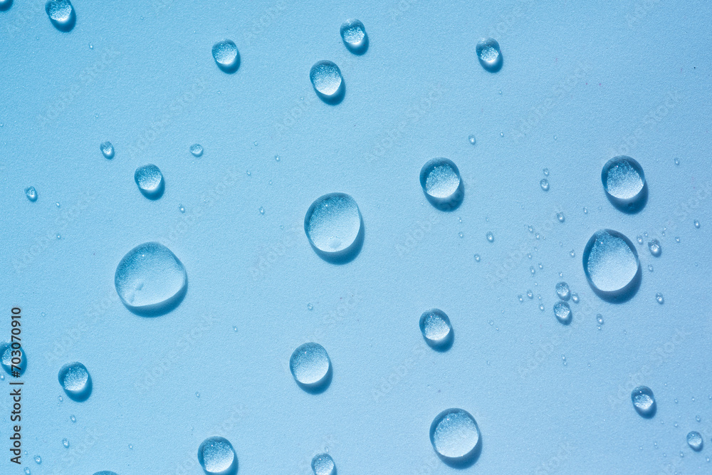 Transparent round drops of clear liquid, hyaluronic acid. Abstract blue cosmetic backdrop with splash, water spray