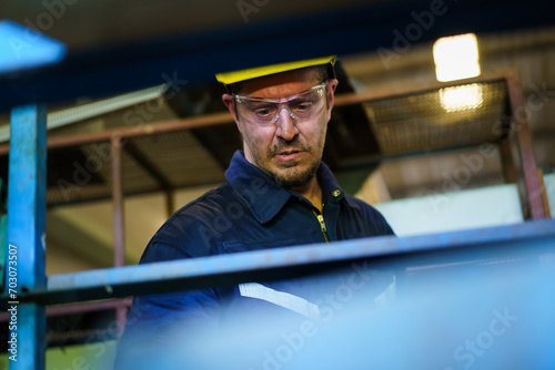 Caucasian white ethnicity worker working in metal lathing factory, male worker inspecting a metal works in factory storage room.