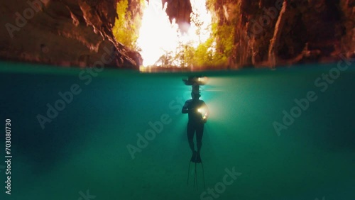 Freediver swims in the cave with torch photo