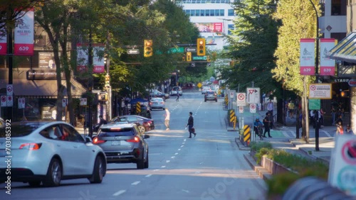 People crossing the street and cars passing in downtown Vancouver, Canada. Slow motion.  photo