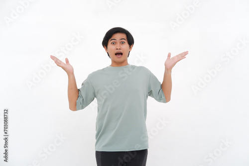 A young Asian man raises his hand with a confused and clueless expression