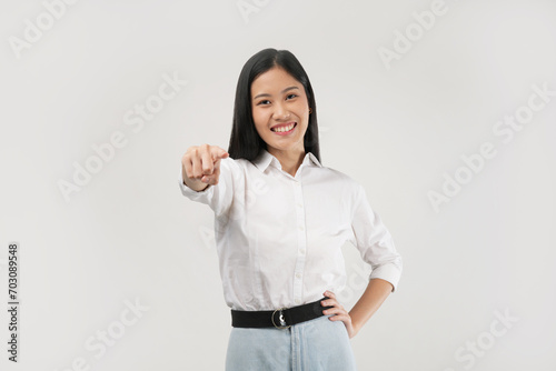 A young Asian woman points forward with a big smile, appearing engaged and enthusiastic, as if addressing or encouraging someone directly