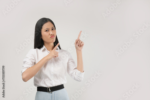 A young Asian woman in a white shirt points with two fingers in different directions, signaling a choice or comparison in a professional setting