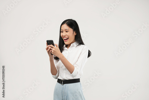 Portrait of a young Asian woman holding her phone feeling excited, shocked having reading news or message and isolated on a white background