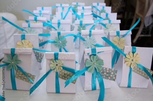 White gift boxes with blue ribbons  and flower emblem on a table