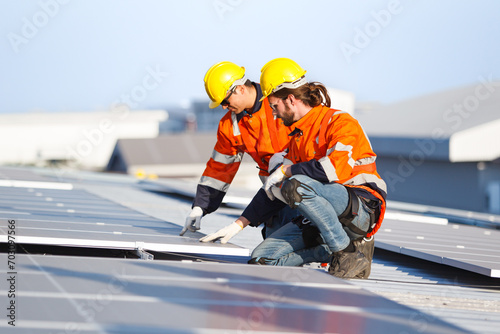 Professional electric engineers survey and inspect solar panels installation on the factory metal sheet roof top.