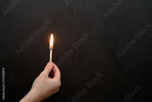 Hand holding a lit match against dark background