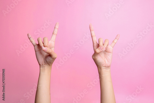 Two hands showing rock sign, rock and roll sign hand gesture isolated over pink background photo