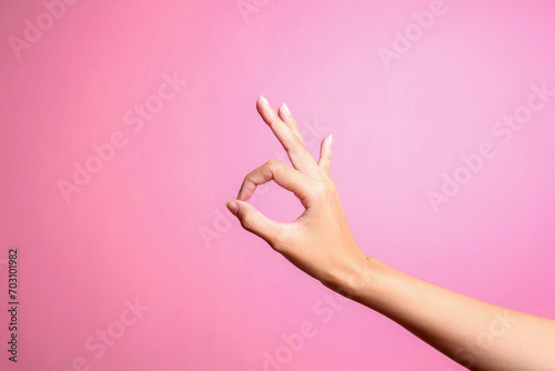 Woman hand showing ok gesture isolated on a pink background. Ok hand sign