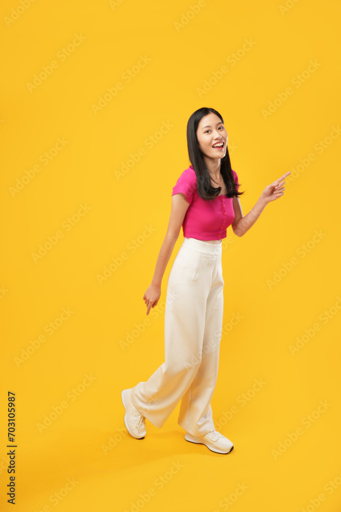 Full body of length, vivid young woman Asian-looking camera moves isolated on a plain yellow background in a studio portrait. People's emotions lifestyle concept Full body of length, vivid young woman Asian-looking camera moves isolated on a plain yellow background in a studio portrait. People's emotions lifestyle concept