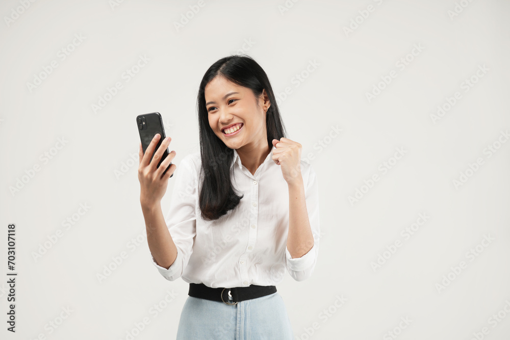 Photo of a young Asian woman smiling and celebrating good news on phone notification,
dressed a white shirt and isolated on a white background. Positive message. Photo of a young Asian woman smiling and celebrating good news on phone notification,
dressed a white shirt and isolated on a white background. Positive message.