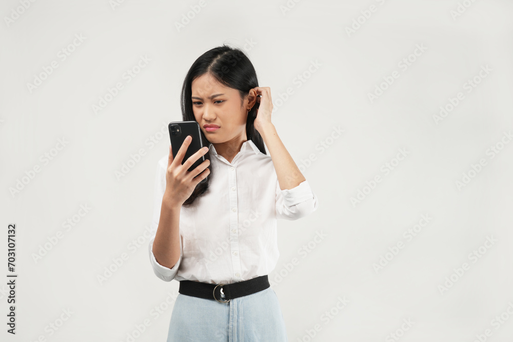 This portrait of a young Asian woman wearing a white shirt, upset talking on a mobile phone, and isolated on a white background. Bad news concept. This portrait of a young Asian woman wearing a white shirt, upset talking on a mobile phone, and isolated on a white background. Bad news concept.