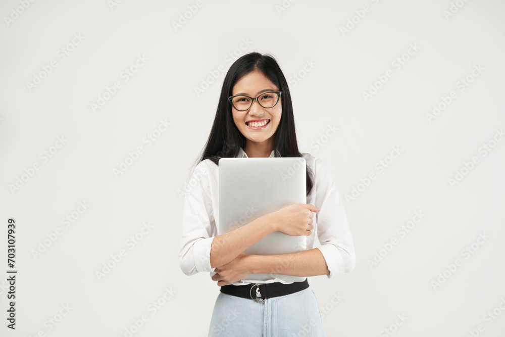 An Asian woman smiles confidently while hugging her laptop, showcasing warmth and professionalism in a bright, modern setting. An Asian woman smiles confidently while hugging her laptop, showcasing warmth and professionalism in a bright, modern setting.
