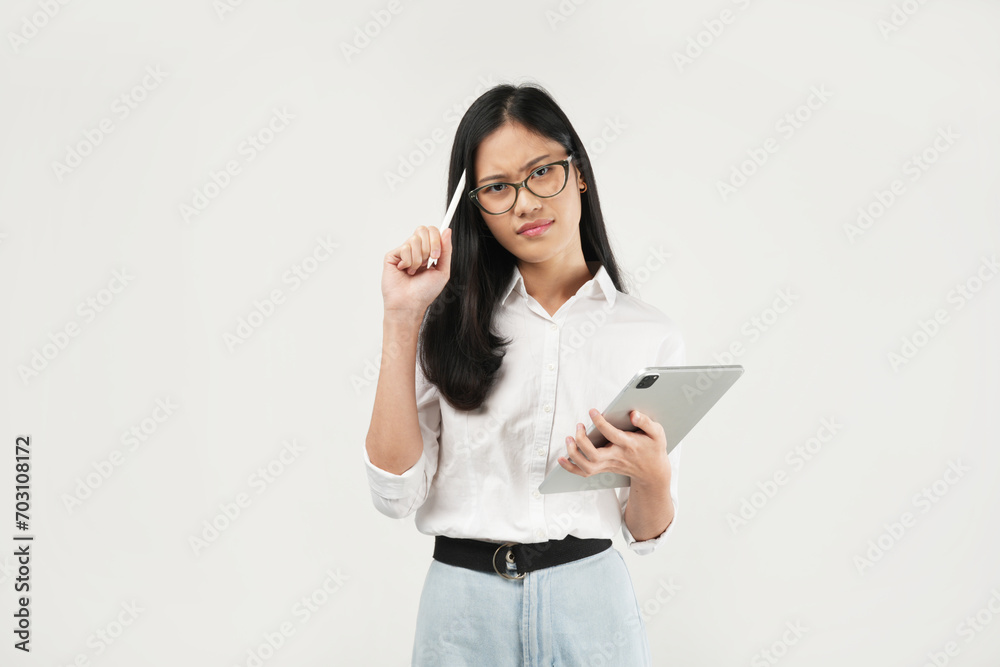 An Asian woman holds a tablet while thoughtfully tapping her pen against her chin, exuding a contemplative and focused demeanor in a professional setting. An Asian woman holds a tablet while thoughtfully tapping her pen against her chin, exuding a contemplative and focused demeanor in a professional setting.