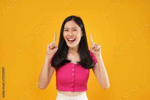 Portrait of a young Asian woman smiling having some idea, concept of creativity, and looking at the camera. Isolated on a yellow background.
