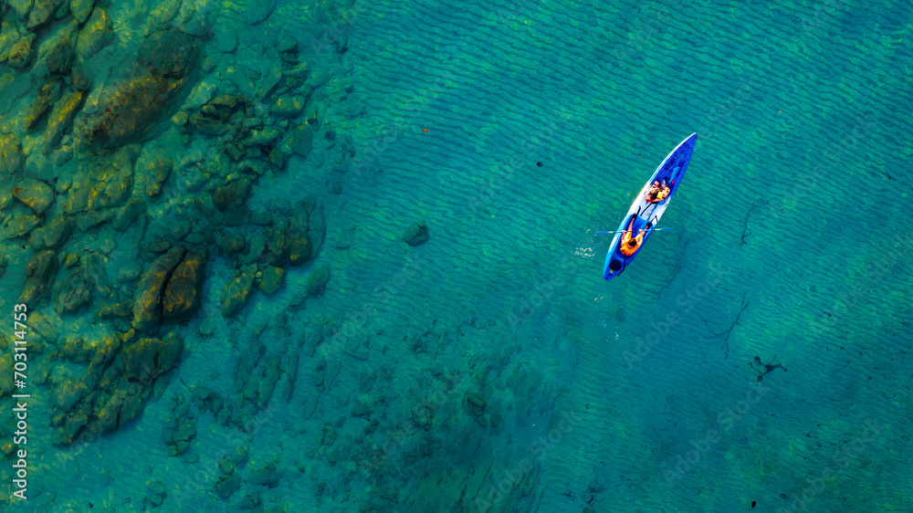 Top view of a woman paddling a yellow and orange kayak on the surface water blue sea. Woman doing water sports activities	