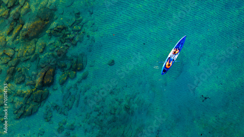 Top view of a woman paddling a yellow and orange kayak on the surface water blue sea. Woman doing water sports activities 