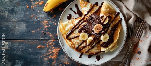 Chocolate and banana crepes served on a white plate, viewed from above with room for text. photo