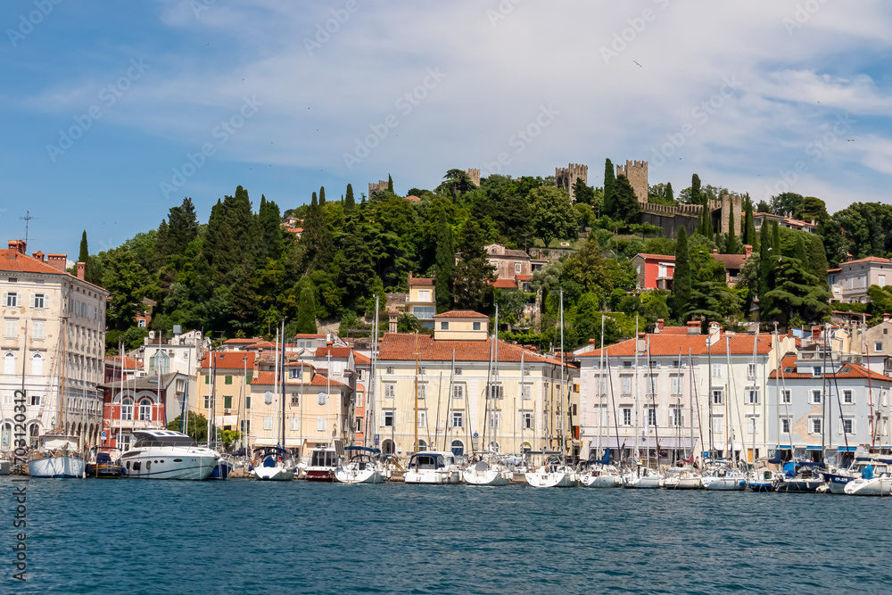 Fishing and sailing boats in serene harbor of coastal town Piran, Slovenia, Europe. Tranquil Venetian port in Adriatic Mediterranean sea. Summer at Slovenian coastline. Scenic view of city wall
