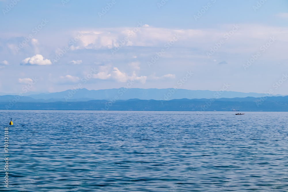 Obraz premium Panoramic view of idyllic coastline seen from Gulf of Piran, Adriatic Mediterranean Sea, Slovenia, Europe. Summer seaside vacation. Distant mountain ranges of Julian Alps. Ships floating in calm water