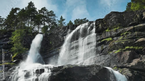 Tvindefossen waterfall cascades from the dark rocky cliffs. photo