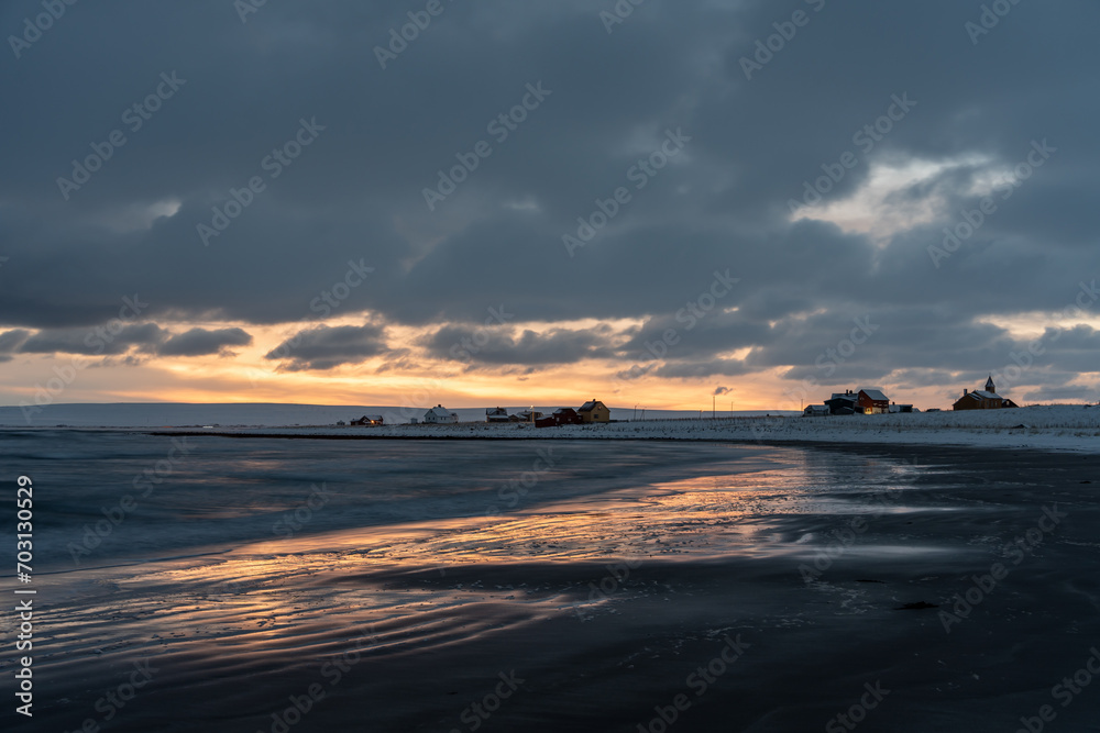 Moody afternoon sky and reflections on wet sand by the sea on a winter afternoon, Skallelv, Northern Norway