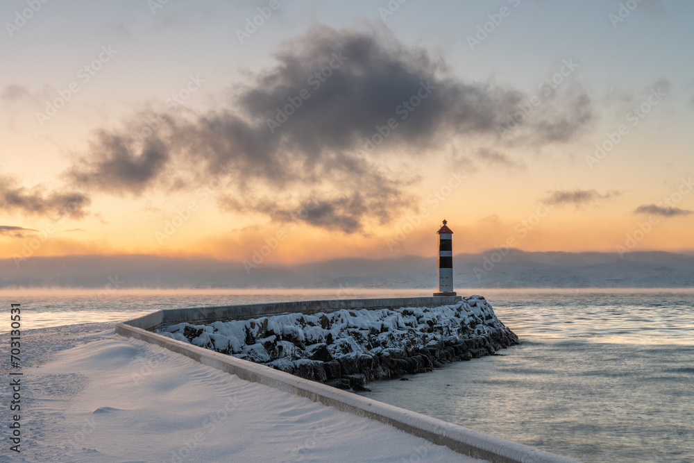 Beacon at the end of a breakwater with beautiful light of the polar night in the background on a cold winter day, Varanger Peninsula, Vestre Jagobselv, Northern Norway
