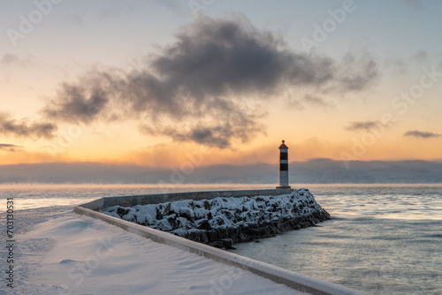 Beacon at the end of a breakwater with beautiful light of the polar night in the background on a cold winter day, Varanger Peninsula, Vestre Jagobselv, Northern Norway photo