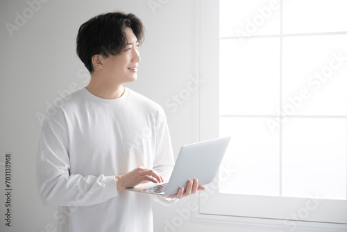 窓際でパソコンを使うハンサムな男性　フリーランス・エンジニア・デザイナーなどのイメージ photo