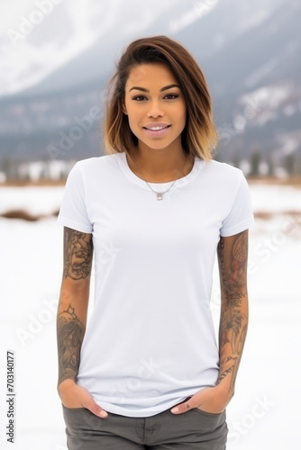 Beautiful tattooed woman wearing an empty mockup blank white t-shirt with snowy mountain in background © Keitma